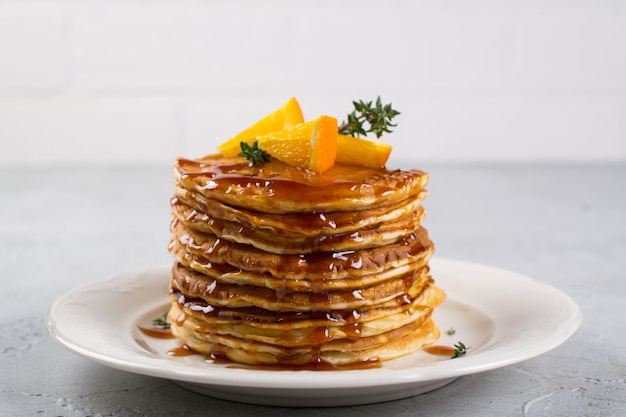 Pila de panqueques con naranja y jarabe de caramelo espolvoreado