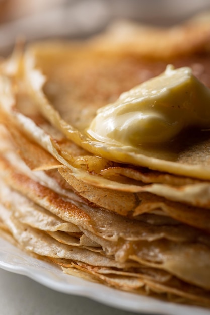 Foto una pila de panqueques con un pedazo de mantequilla derretida