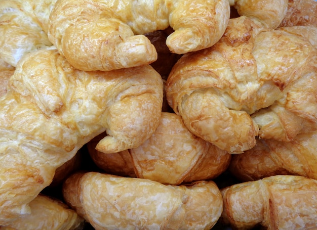 Pila de pasteles frescos del cruasán en la panadería, para el fondo