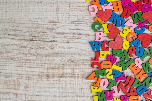 Pila de pequeñas letras de madera multicolores para la educación primaria Letras en inglés en un orden caótico sobre una mesa de madera