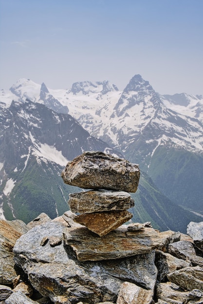 Pila de piedras en la cima de la montaña contra los picos nevados de las montañas