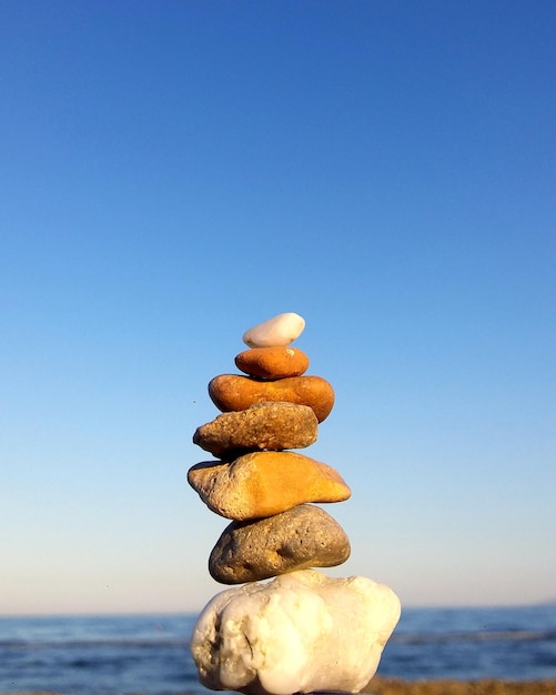 Foto una pila de piedras en el mar contra un cielo azul claro