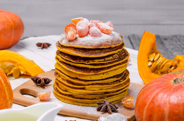 Una pila de punkcakes de calabaza hechos en casa con azúcar en polvo encima y kumquat confitado.