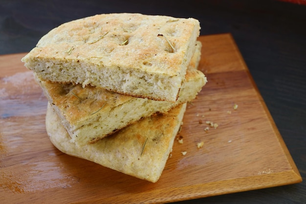 Pila de rebanadas de pan de focaccia de romero en tablero de madera