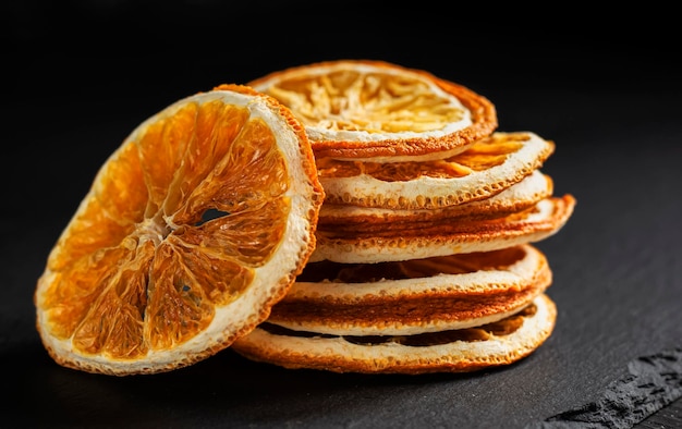 Una pila de rodajas redondas de naranja seca sobre un fondo negro