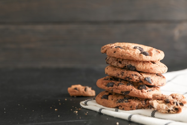 Pila de sabrosas galletas de chispas de chocolate en servilleta y fondo de madera. Espacio para texto