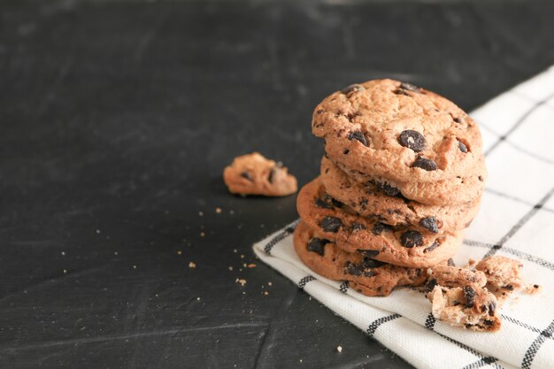 Pila de sabrosas galletas de chispas de chocolate en servilleta y fondo de madera. Espacio para texto