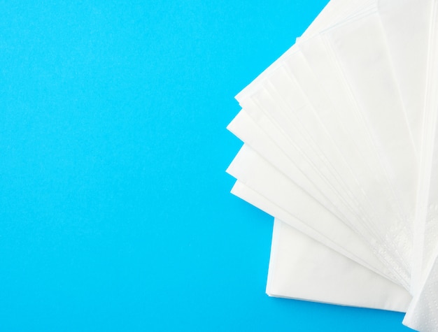 Foto pila de servilletas de papel blanco sobre un fondo azul.