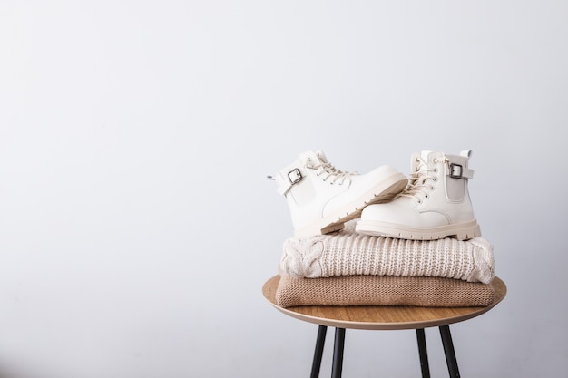 Pila de suéteres y botas sobre una mesa de madera. Lugar para el texto. Publicidad