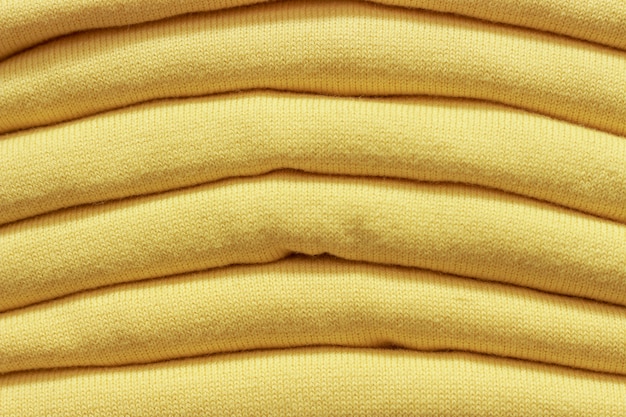 Una pila de suéteres de punto amarillo close-up, textura de fondo.