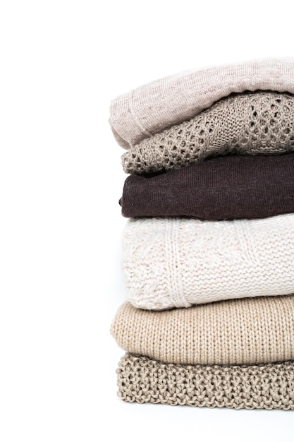 Pila de suéteres de punto de lana marrón aislado sobre fondo blanco.