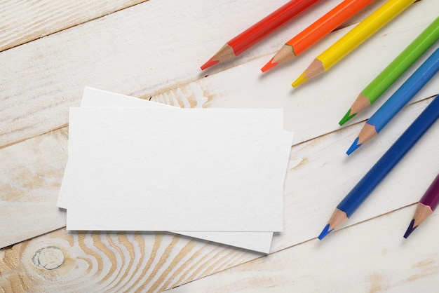 Pila de tarjetas de visita con lápices de colores sobre una mesa de tablones de madera