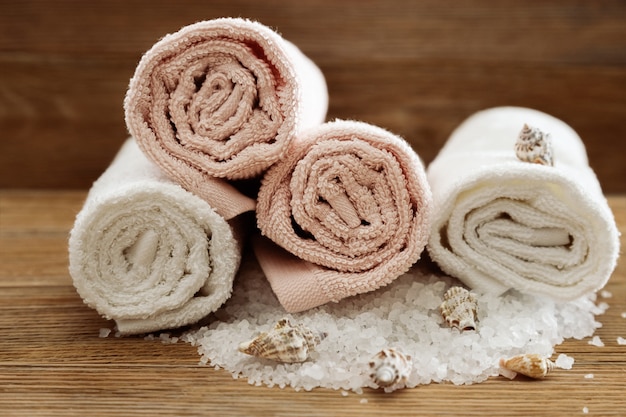 Pila de toallas de baño en la mesa de madera. Toallas de algodón blanco y rosa. Concepto de spa. Foto tonificada