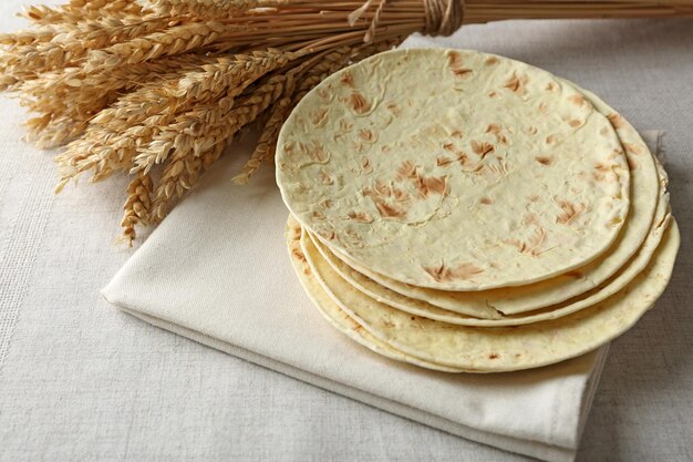 Pila de tortilla de harina de trigo integral casera en servilleta sobre fondo claro