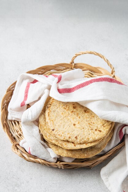 Pila de tortillas de maíz mexicanas en una bandeja de mimbre cubierta con papel de cocina