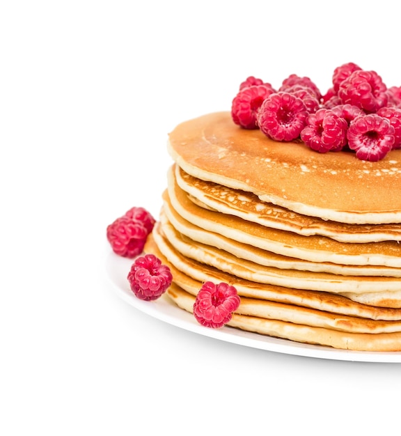 Pila de tortitas con frambuesas en un plato aislado sobre fondo blanco.