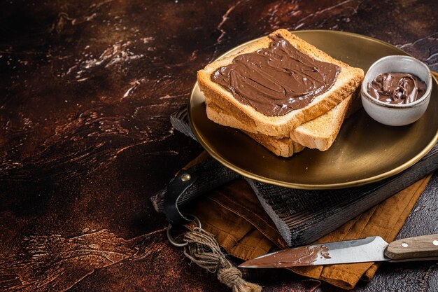 Pila de tostadas con crema de chocolate y avellanas en plato Fondo oscuro Vista superior Espacio de copia