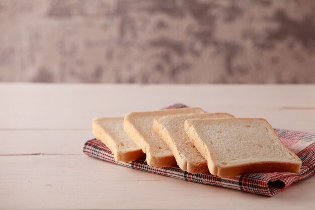 Una pila de tostadas de pan rebanado sobre fondo de madera blanca