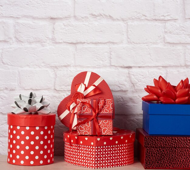 Pila de varias cajas con regalos en la pared de ladrillo blanco.