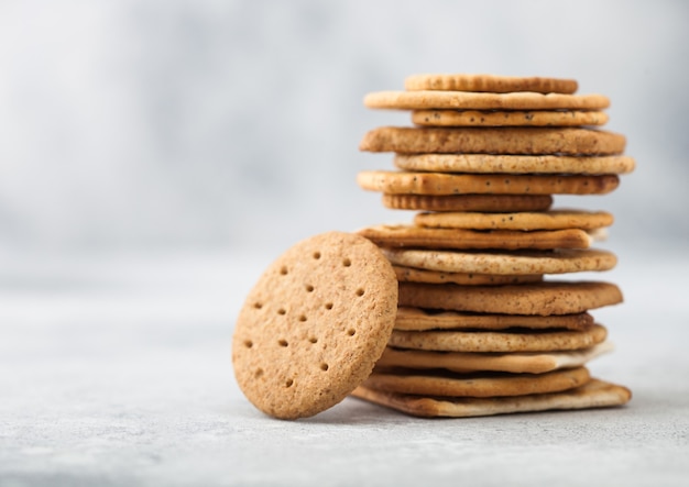 Pila de varias galletas crujientes orgánicas de pan plano plano de trigo, centeno y maíz con sésamo y sal sobre un fondo claro. Espacio para texto