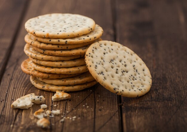 Pila de varias galletas de pan plano plano de trigo crujiente orgánico con sésamo y sal sobre fondo de madera.