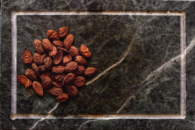 Pila de vista superior de primer plano de nueces de almendras en la superficie de piedra con espacio de copia.