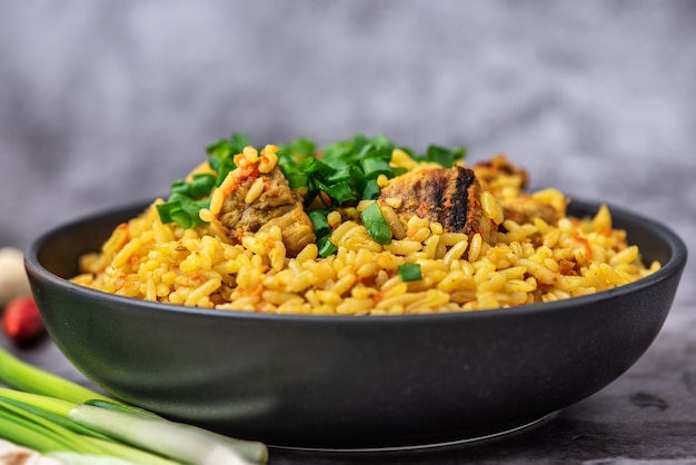 Pilaf de arroz con carne de zanahoria y cebolla sobre fondo gris. Vista lateral.