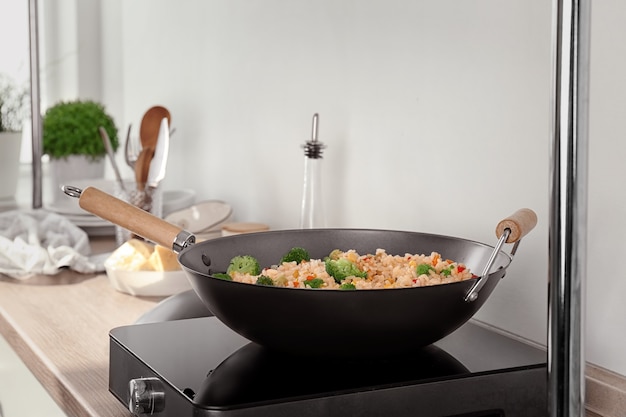 Foto pilaf de arroz delicioso con brócoli en wok en cocina eléctrica