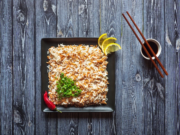 Pilaf de arroz oriental con orzo en un plato sobre una superficie de madera oscura. Vista superior.