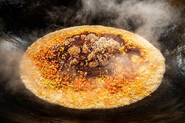 Pilaf auf dem Feuer in einem großen Kessel kochen, Lamm und Gemüse kochen, Karotten und Zwiebeln braten