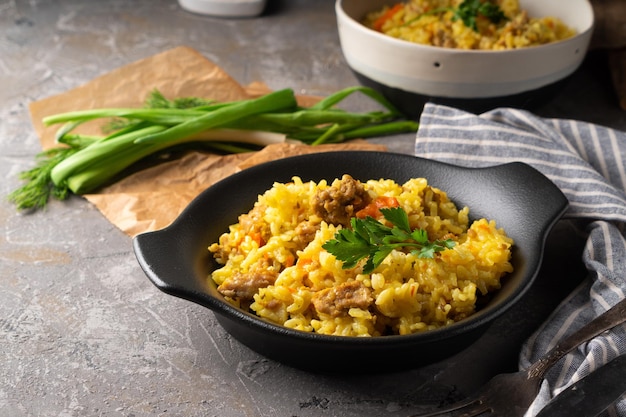 Pilaf azian tradicional servido en plato sobre fondo gris