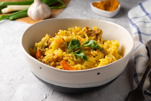 Pilaf azian tradicional servido en plato sobre fondo gris