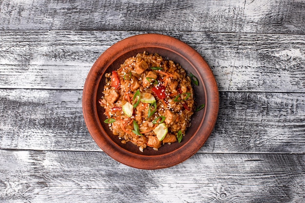 Pilaf con carne, verduras, pollo, pilaf casero sobre un fondo blanco de madera