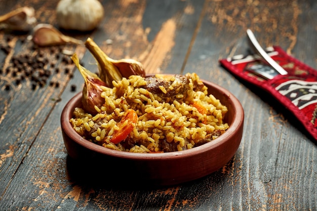 Pilaf clássico com alho bovino e cenoura em prato de barro sobre fundo de madeira Rústico