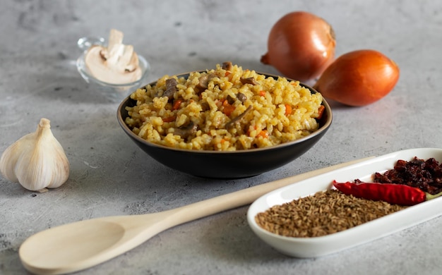 Pilaf com cogumelos e ingredientes para ele em um fundo claro Horizontal