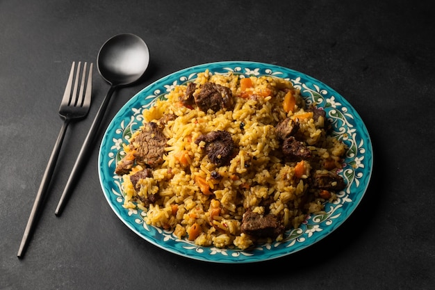 Pilaf fragante con vista superior de carne y verduras en un plato sobre fondo negro con espacio de copia