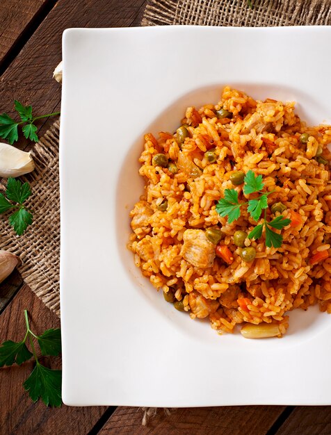 Pilaf con pollo, zanahoria y guisantes verdes en plato blanco