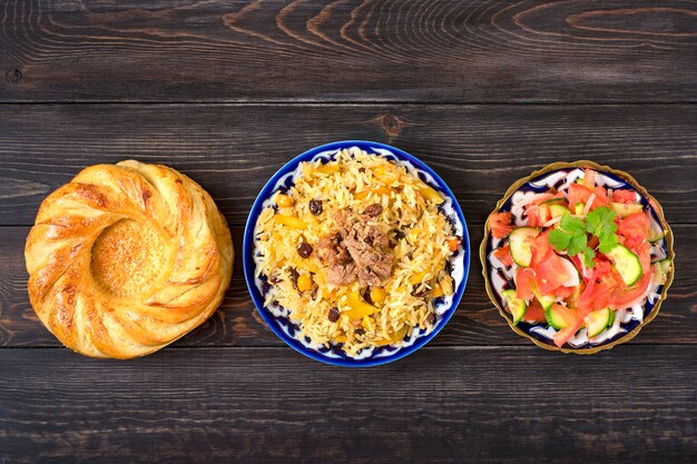 Pilaf uzbeque nacional com carne, salada achichuk de tomate, pepino, cebola no prato com tradicional