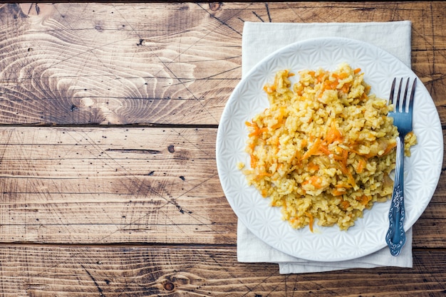 Pilaf vegetariano oriental con arroz y verduras en una mesa de madera.