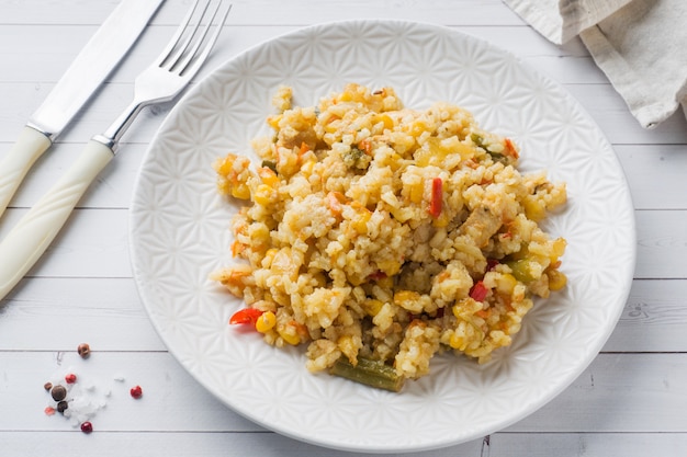 Pilaf con verduras y pollo en una placa gris en una luz.