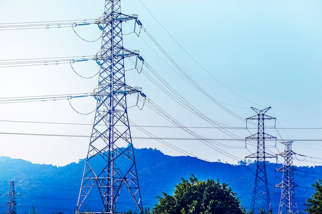 Pilão da transmissão de energia elétrica em silhueta contra o céu azul no d