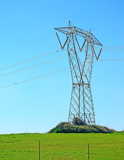 Foto pilão de eletricidade em uma grama verde sob um céu azul