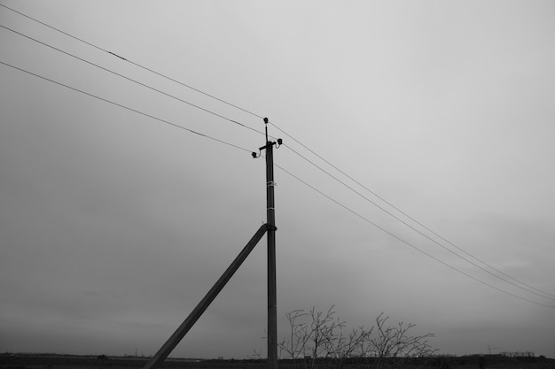 Pilar com fios elétricos em meio a névoa escura, paisagem sombria