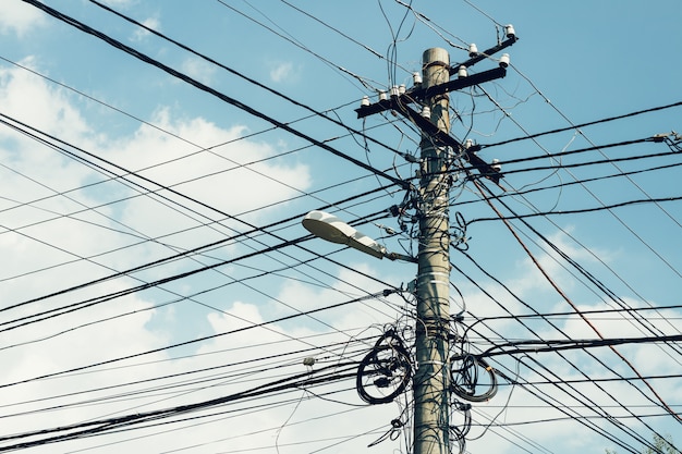 Pilar con una gran cantidad de cables y una farola en el fondo del cielo