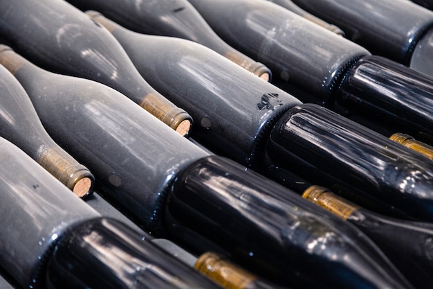 Pilas de botellas de vino tendidas en bastidores en la antigua bodega o cueva