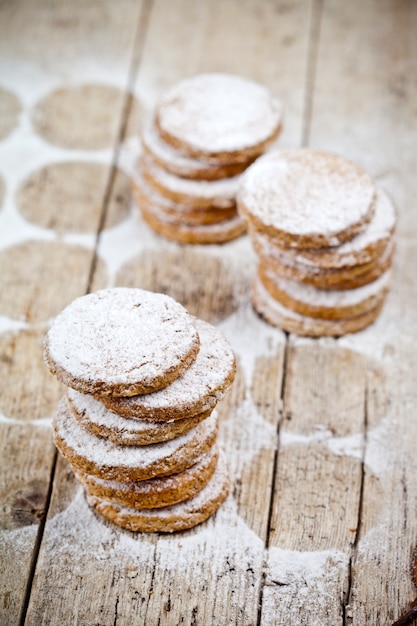 Pilas de galletas de avena fresca con polvo de azúcar en la mesa de madera rústica