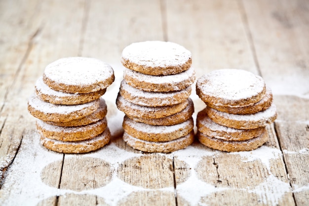 Pilas de galletas de avena fresca con polvo de azúcar en la mesa de madera rústica