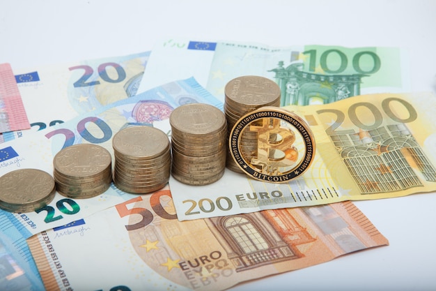 Pilas de monedas, billetes en euros y bitcoins