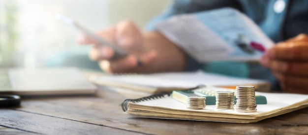 Pilas de monedas en una mesa de madera con calculadora en el fondo un hombre comprueba las facturas del hogar