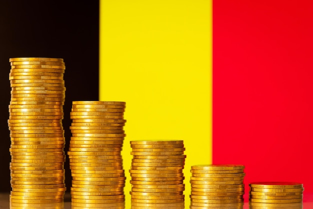 Pilas de monedas de oro contra la bandera de Bélgica